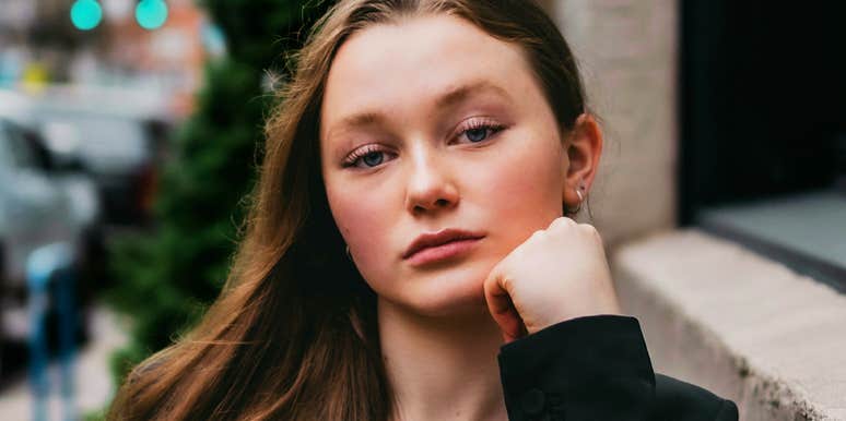 A woman looking at the camera with a calm and strong expression while resting her chin on her hand; illustrating the quick habits of emotional regulation and composure used to navigate high-stress situations.