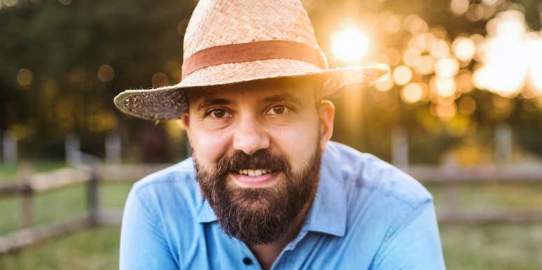 A middle-aged man smiling outdoors with a wholesome expression