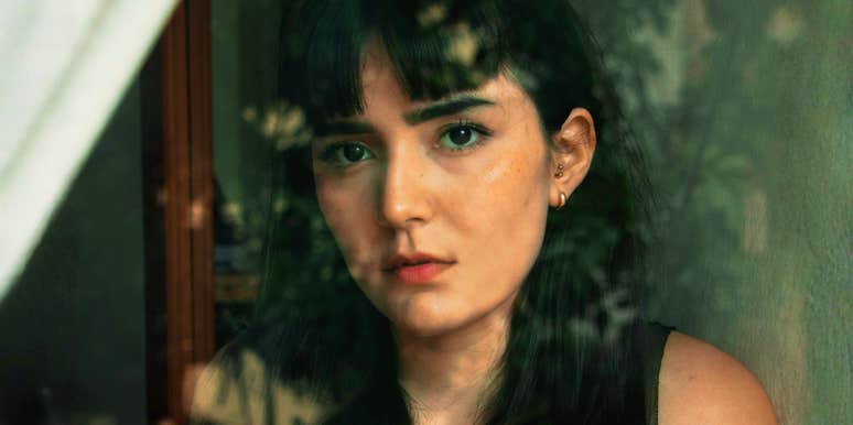 A woman looking thoughtfully out a window, capturing the internal conflict of someone who senses a repetitive pattern in their life but hasn't yet acted on it.