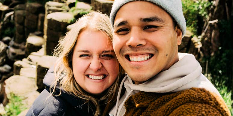 A couple smiling while capturing a photo on their phones during a date outside; illustrating the simple, everyday rituals that maintain emotional intimacy in a healthy partnership.