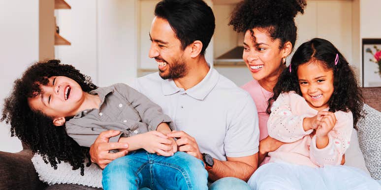 Young family happily playing on couch as part of an old-school tradition 