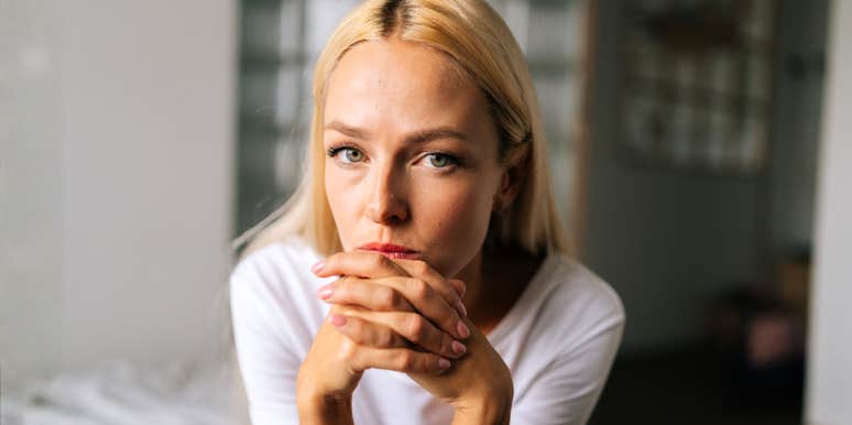 A close-up portrait of a blonde woman with a pensive and sad expression, capturing the silent emotional burden and 'painful secrets' many wives feel unable to share with their husbands.
