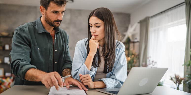 couple at home together signing paper in clipboard