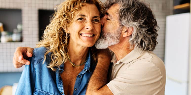 A mature man and woman in their 60s working together in a kitchen to prep healthy food; illustrating the shared activities and physical closeness that fuel a lasting romantic connection in older age.