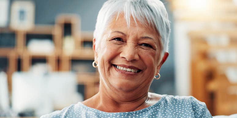 smiling elderly woman sitting on couch at home