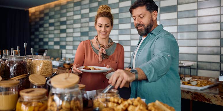 hotel guests putting breakfast on plates during buffet