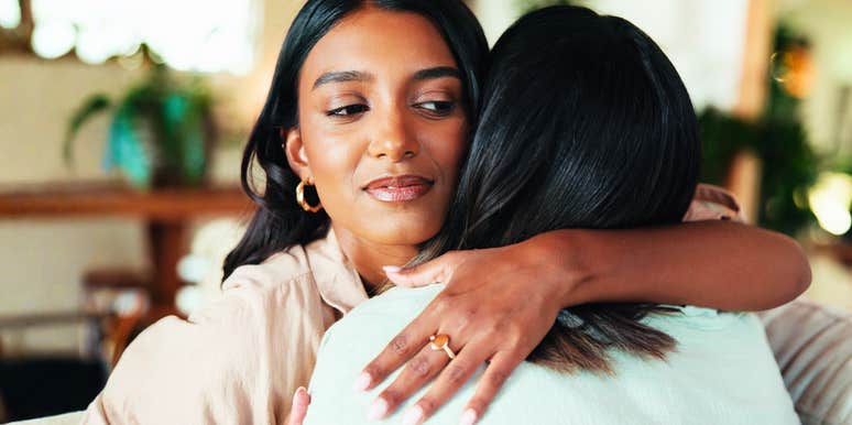 A close-up of an embrace between two people where one person's expression suggests deceit and jealousy; illustrating the 'polite' but secretly manipulative tactics used in toxic relationships.