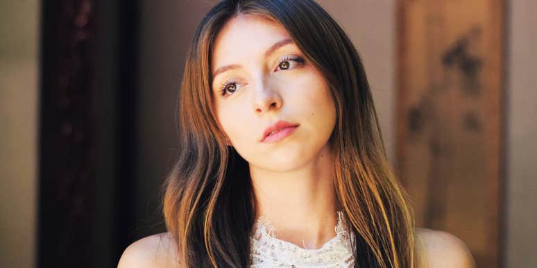 A woman in deep thought with a sad, pensive gaze; illustrating the long-term impact on self-worth caused by passive-aggressive and 'harmless' comments from a mother.