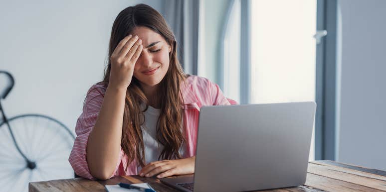 frustrated woman sitting in front of open laptop at desk