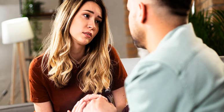A woman showing visible signs of regret while talking to her partner; illustrating the restorative communication process and the steps taken to heal a broken bond after a breach of honesty.