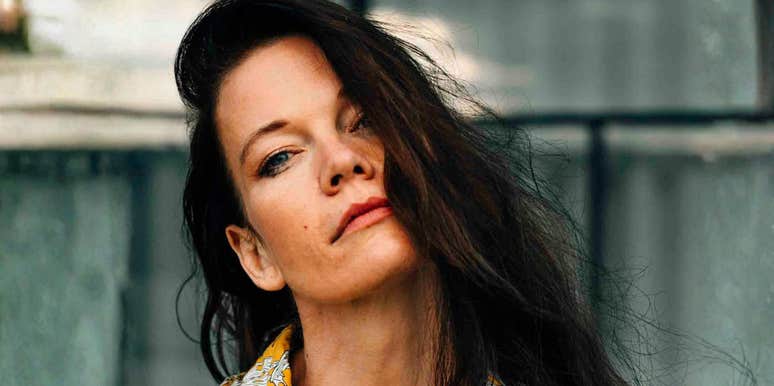 A portrait of a fashionable woman in a yellow floral top against a Berlin backdrop; illustrating the 'covert' nature of toxic behavior and the common traits that high-conflict personalities use to manipulate their environment.