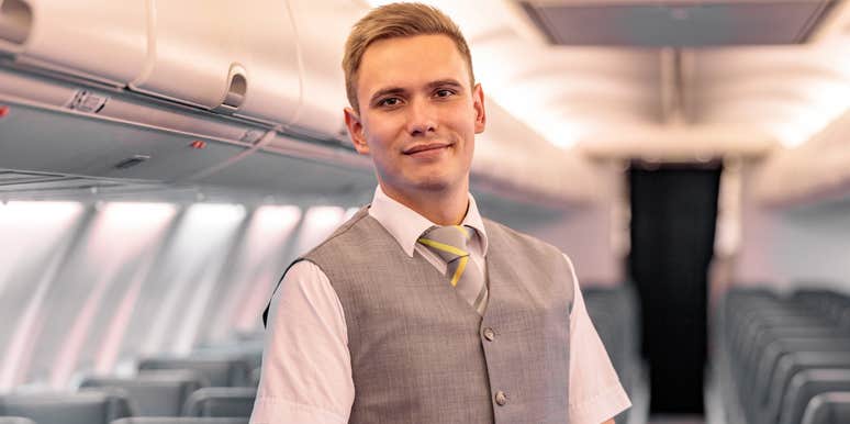 smiling male flight attendant on empty plane