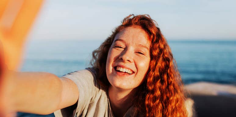 A carefree woman smiling happily at the camera during summer; illustrating the 'emotional clarity' that arrives after a person successfully navigates the challenging feelings that precede a lasting life change.
