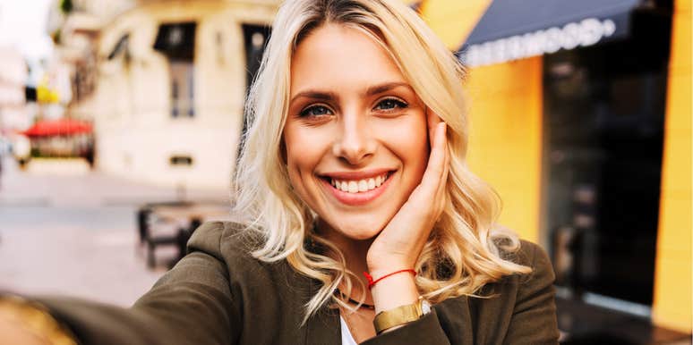 A woman posing for a curated selfie with a bright, focused smile; illustrating the 'over-calculated' online persona that some studies link to decreased perceived trustworthiness among male viewers.