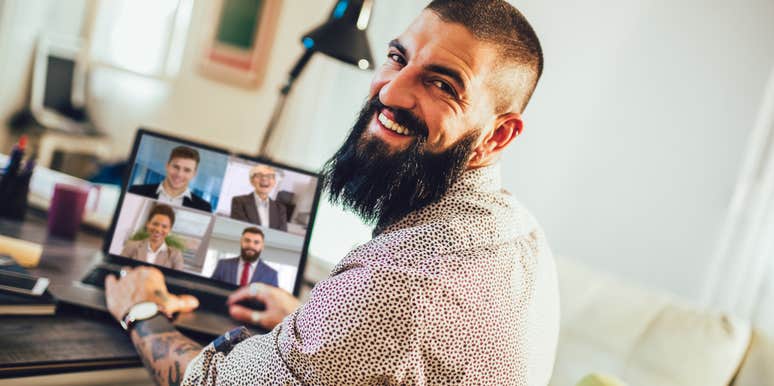 A man with visible tattoos working on a computer in a home setting; illustrating the change in attraction standards where professional focus and domestic stability are key factors in male desirability.
