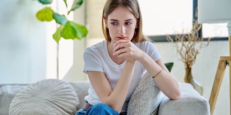 woman thinking while sitting on couch at home