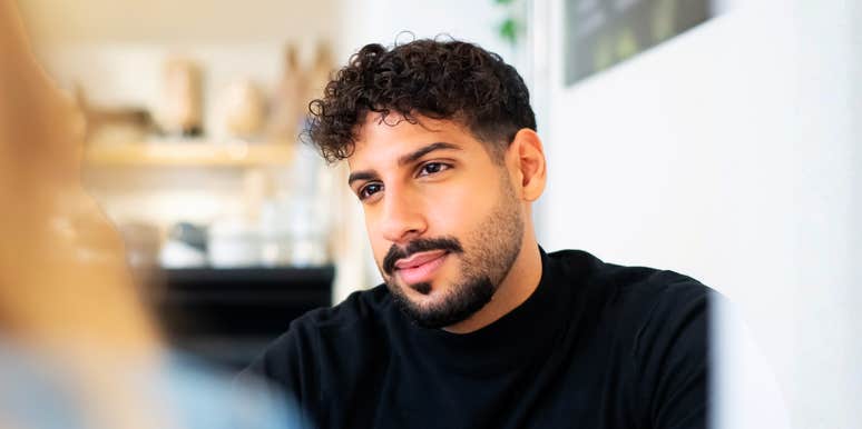 A man engaged in a casual conversation, showing a focused and thoughtful gaze; illustrating the 'social cues'—such as deep engagement and processing speed—that signal intelligence to others.