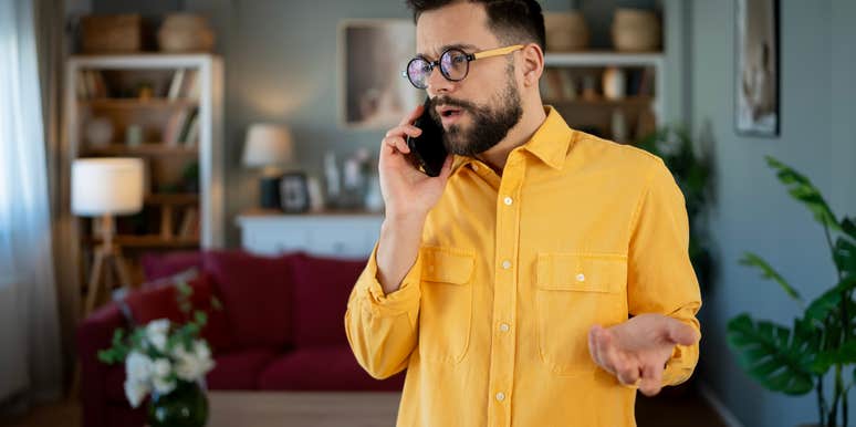 man standing at home talking on phone during tense conversation