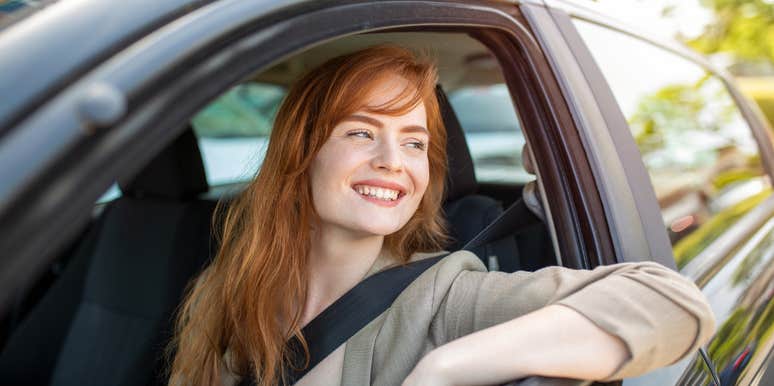 smiling woman sitting in car with window down