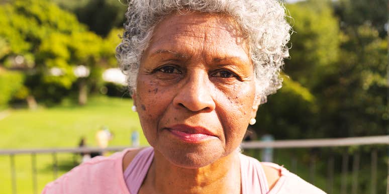 A close-up lifestyle portrait of an elegant mature woman with gray hair looking forward with a calm, knowing expression