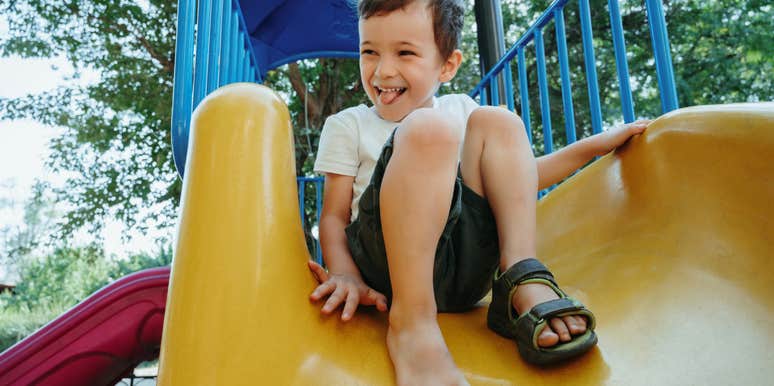 little boy going down slide at park
