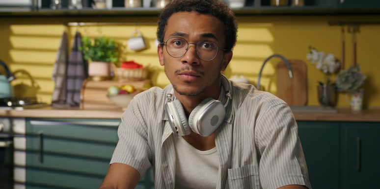 thoughtful gen z man sitting with headphones around his neck