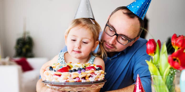 A dedicated father celebrating a birthday milestone with his young daughter in a festively decorated room; illustrating 'equitable labor' and the shift toward fathers taking full ownership of family event planning.