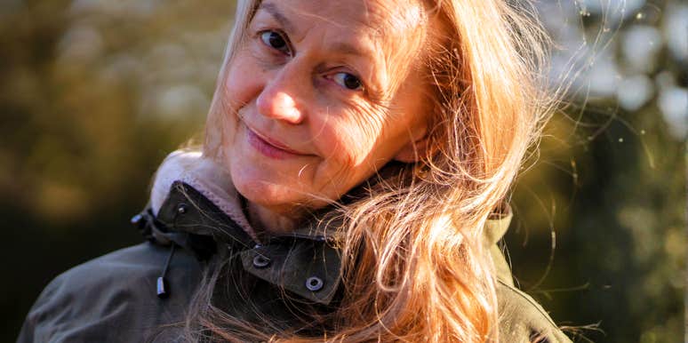 An elderly 60+ beautiful woman with a kind smile is walking outdoors on a sunny autumn day, a happy old lady, a grandmother takes care of her appearance, natural beauty with wrinkles portrait closeup.