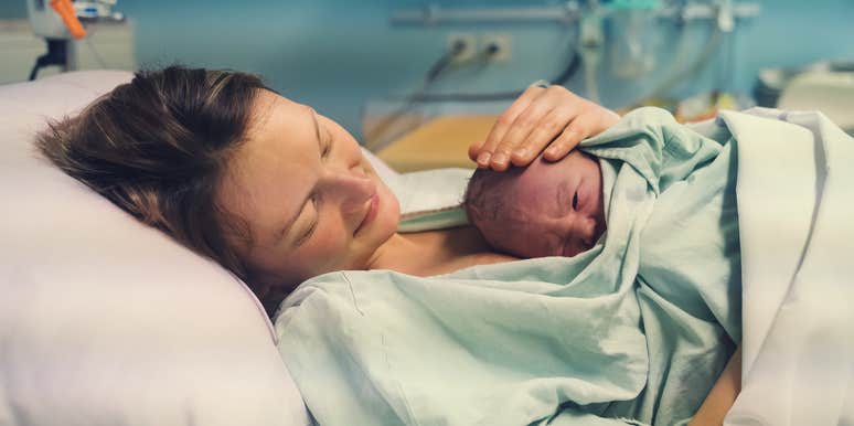 mom holding newborn baby in hospital bed