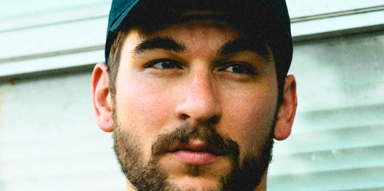 An attractive man wearing a classic baseball hat looking forward with a relaxed, gentle gaze; a visual representation of 'the grounded confidant' and the old-fashioned language that makes a husband irresistible.