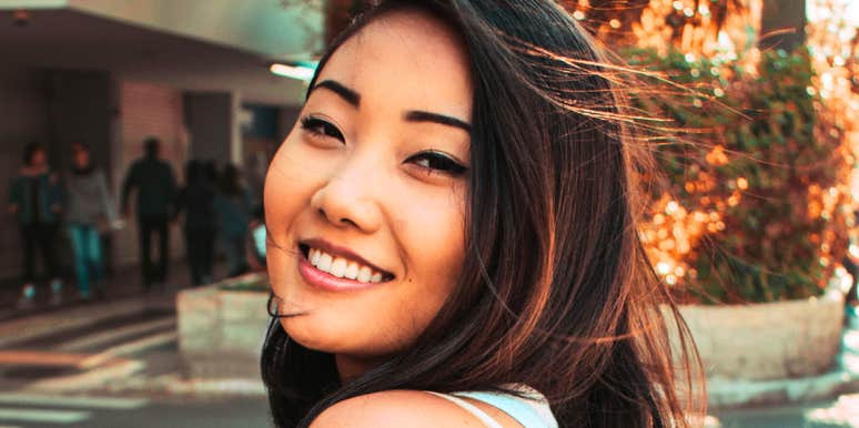 A happy woman looking back over her shoulder with a gentle smile and kind eyes; a visual representation of 'the comfort return' and the unforgettable traits of people you think about years later.