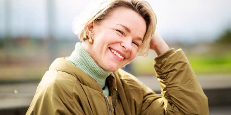 Smiling woman standing outdoors in a calm, confident pose, illustrating the habits of people who build success through effort and mindset