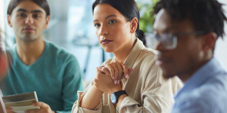 woman surrounded by colleagues and staying silent during important work meeting