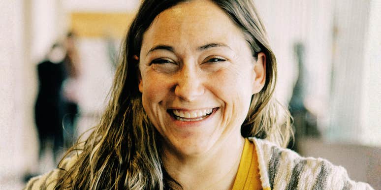 A wholesome woman smiling warmly with genuine, unforced happiness; a visual representation of 'the earnest anchor' and the classic character traits that stay in a partner's mind for years.