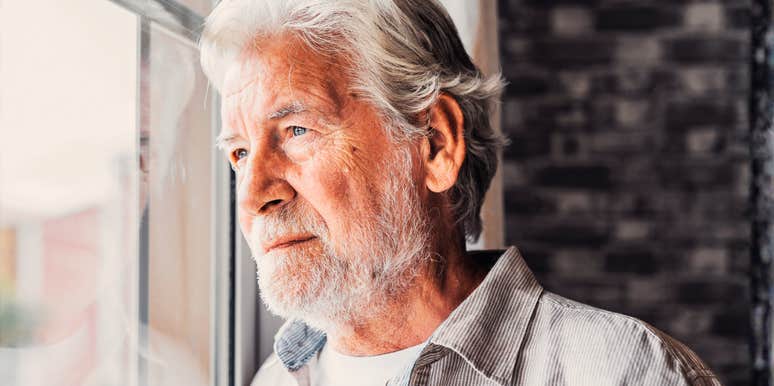 A close-up side profile of a mature, middle-aged grandfather lost in thought while looking through a window; illustrating a 'post-career recalibration' and the quiet introspection that comes with re-evaluating what really matters.