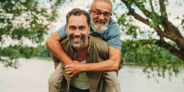 intuitive adult man giving his dad a piggyback ride