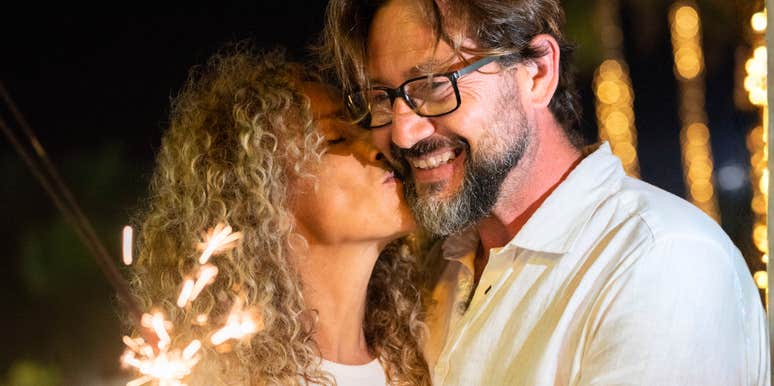 Close-up of a happy wife kissing her husband's cheek outdoors in warm, natural sunlight; illustrating 'the relational pride framework' where vocal appreciation replaces habitual domestic venting.