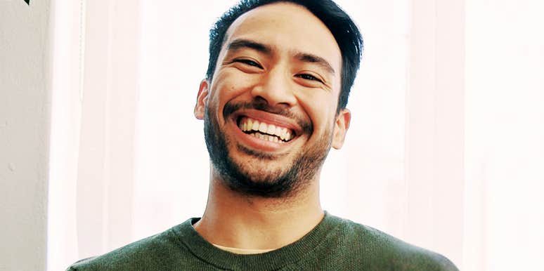 A close-up portrait of a happy, man smiling and laughing while; illustrating natural, unforced positive body language and digital attraction.