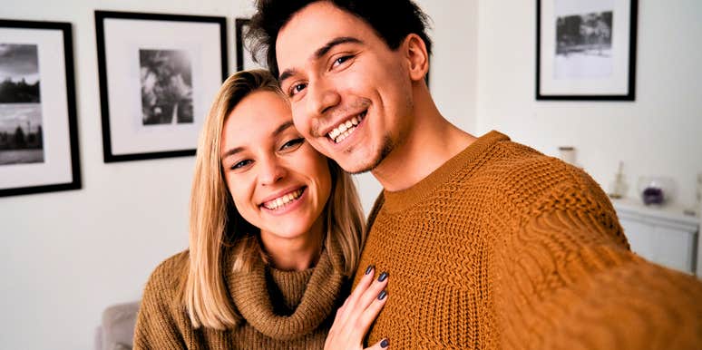 happy millennial couple hugging and taking a photo