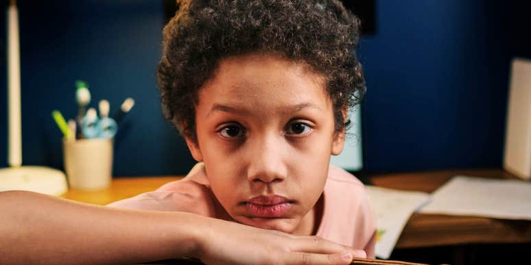 A young kid looking down thoughtfully on chair, capturing the emotional processing of a mistake, internal reflection, and growing moral awareness.