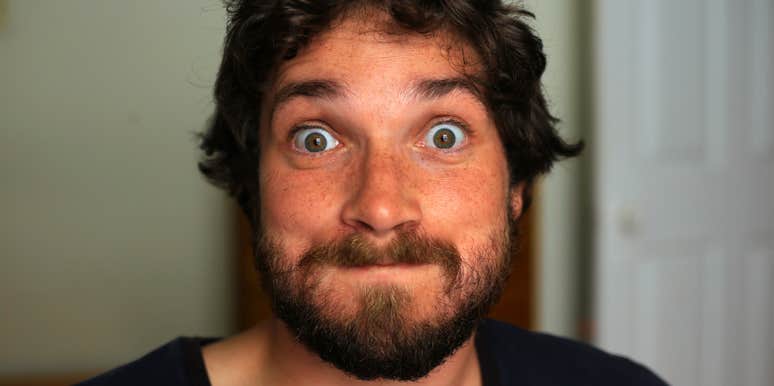 A portrait of a man making a bizarre, wide-eyed facial expression into the camera, illustrating psychological dysregulation, erratic communication, and social impulsivity.