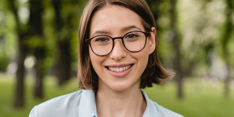 Woman with intimidating intelligence smiling wearing glasses outdoors