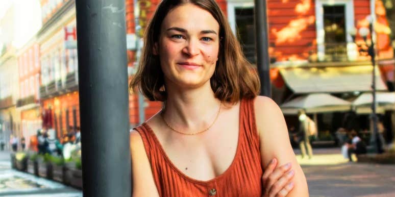 A close-up outdoor portrait of a joyful woman exploring a historic Mexican town during the day; illustrating 'the internal belonging paradox' where a beautiful environment cannot replace deep internal fulfillment.