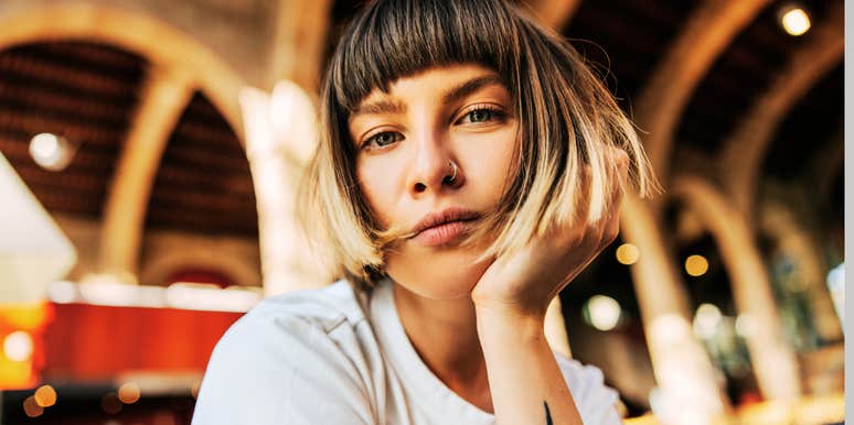 A close-up portrait of an attractive European woman with short hair looking directly into the camera with an intense, discerning expression.