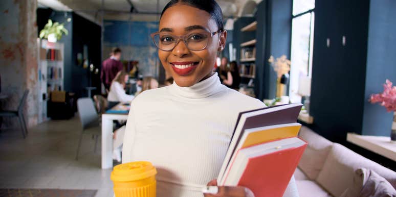 millennial woman smiling in the workplace holding her work