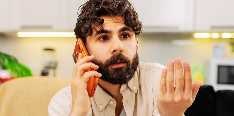 An annoyed man gesturing with his hand while making a phone call indoors, symbolizing marital tension, communication breakdown, and loss of respect.