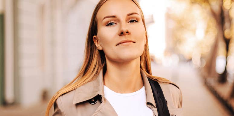 A professional woman smiling confidently in a modern setting, symbolizing emotional resilience, self-possession, and healthy interpersonal boundaries.