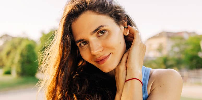 A woman sitting comfortably outdoors with a serene, attentive expression, symbolizing social intelligence, active listening, and conversational ease.