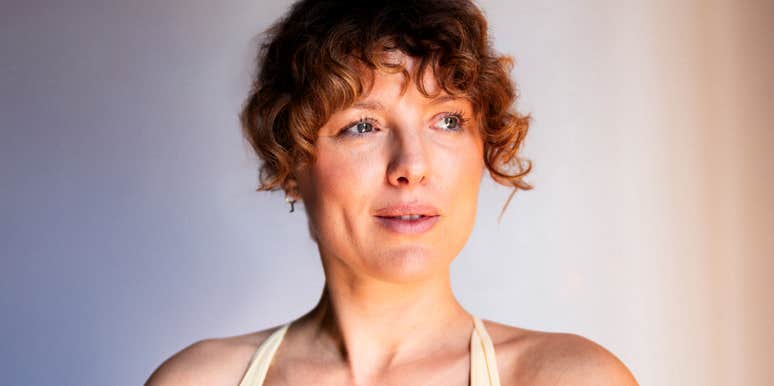 A woman practicing mindfulness meditation indoors with a serene facial expression, symbolizing inner calm, emotional balance, and holistic wellness.