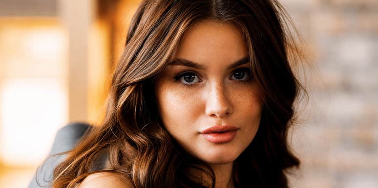 A young woman with long wavy hair looking straight into the lens indoors, symbolizing poise, personal boundaries, and effortless respect.